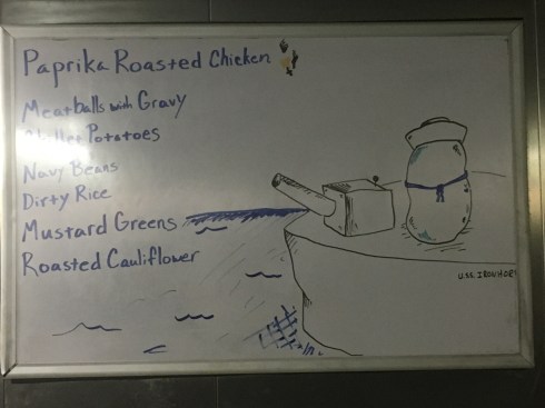 Picture of a bean, dressed in a sailor outfit, standing on the deck of a military battle ship